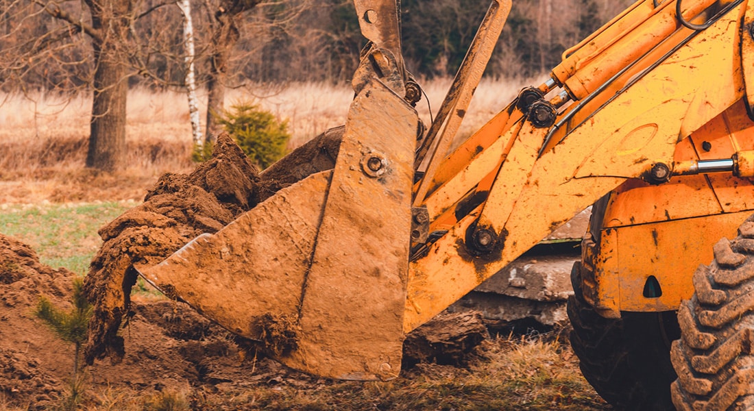 Grader clearing and leveling of the soil to install concrete slabs